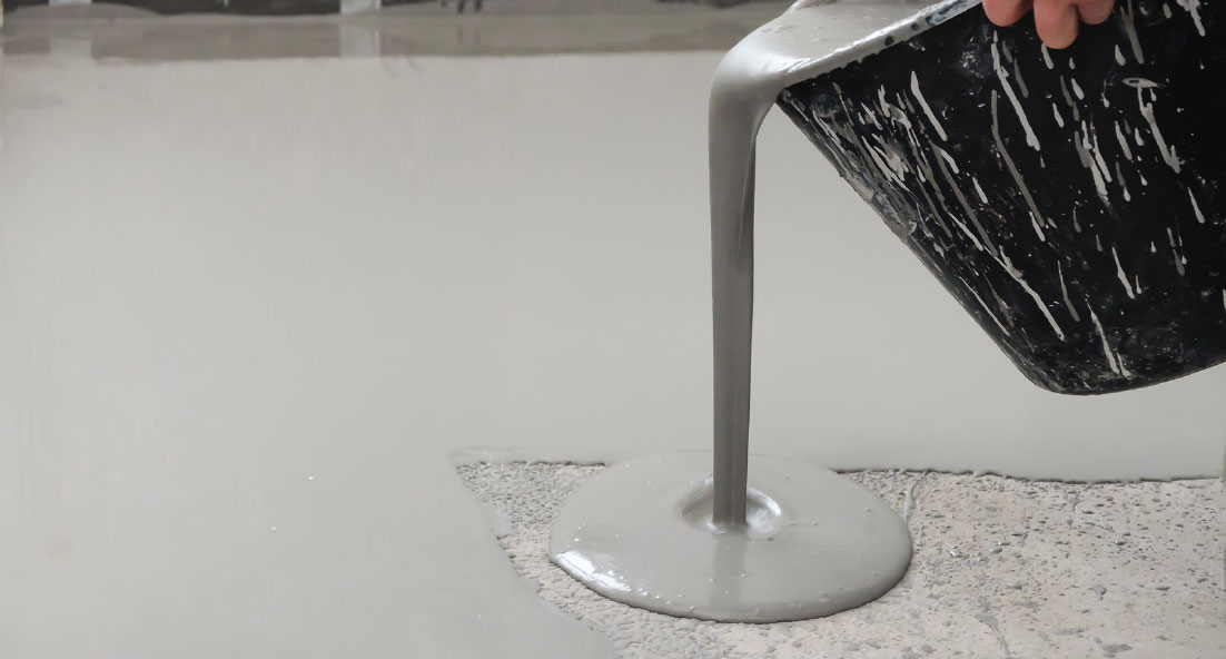 pouring mixture from a bucket onto an industrial floor
